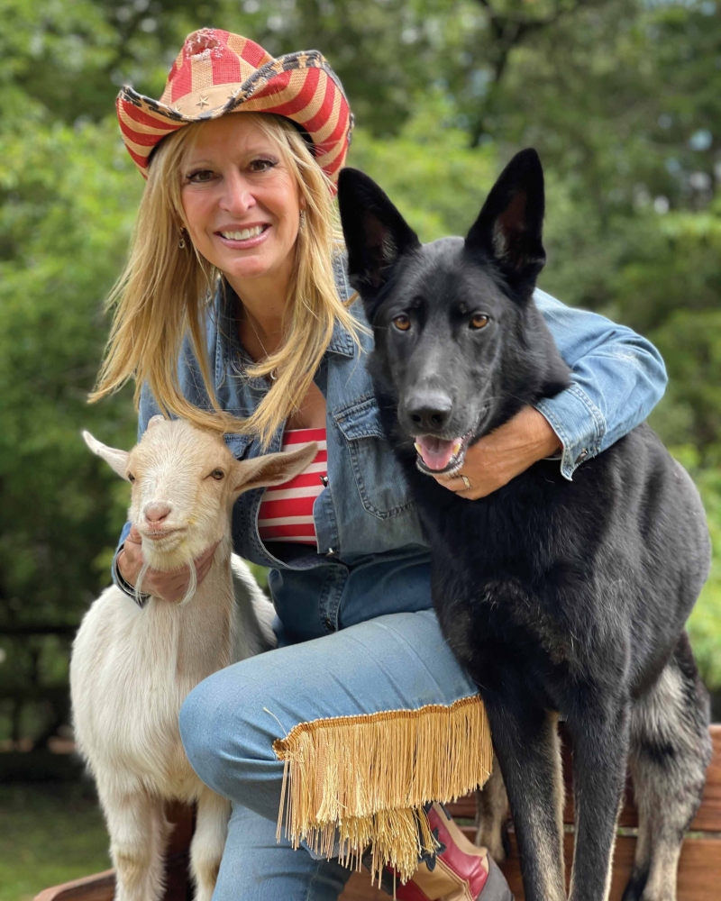 Laurie Zaleski with Tucker the dog and Nemo the Goat at Funny Farm smiling at camera